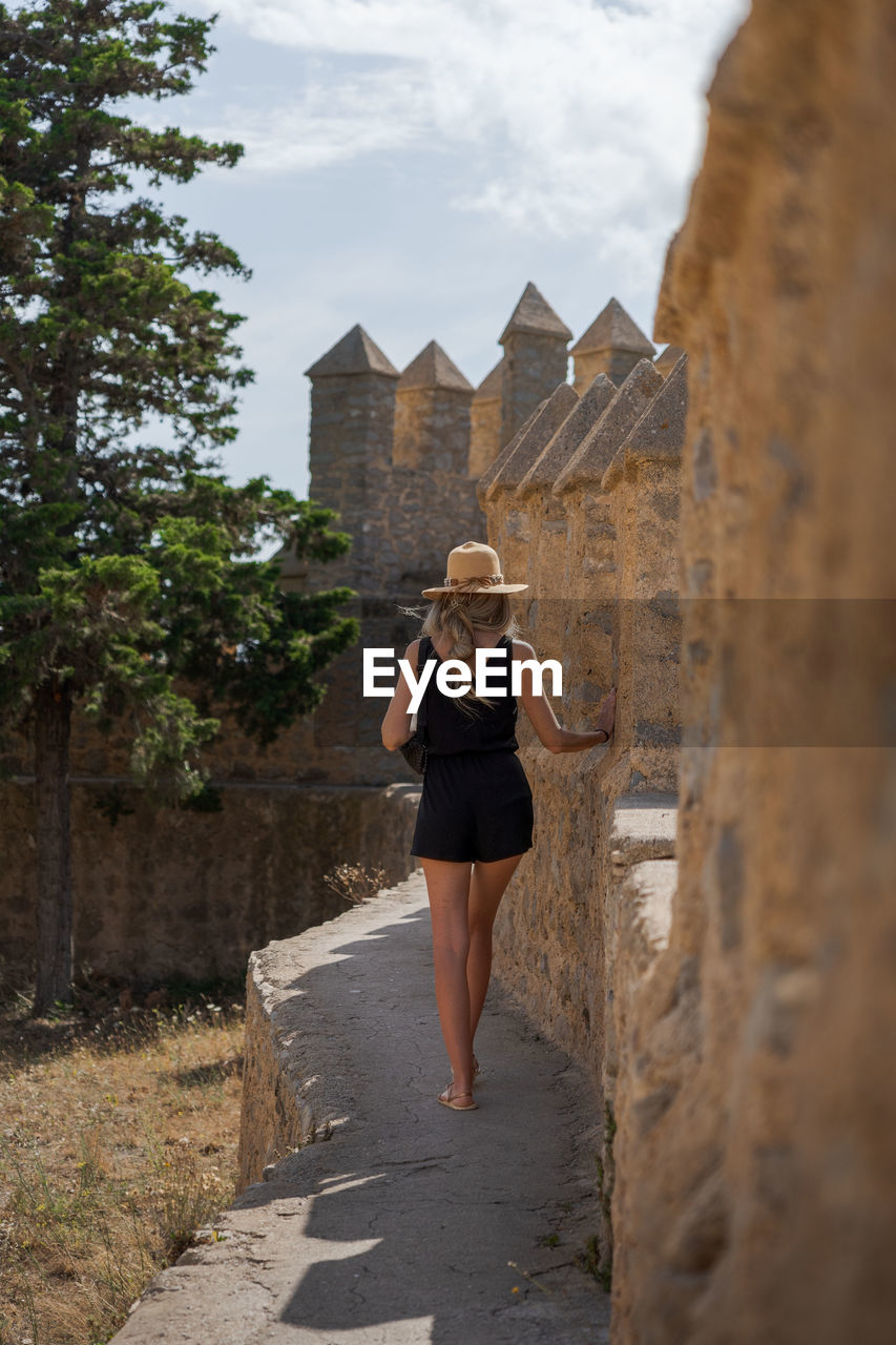 rear view of woman walking on footpath against sky