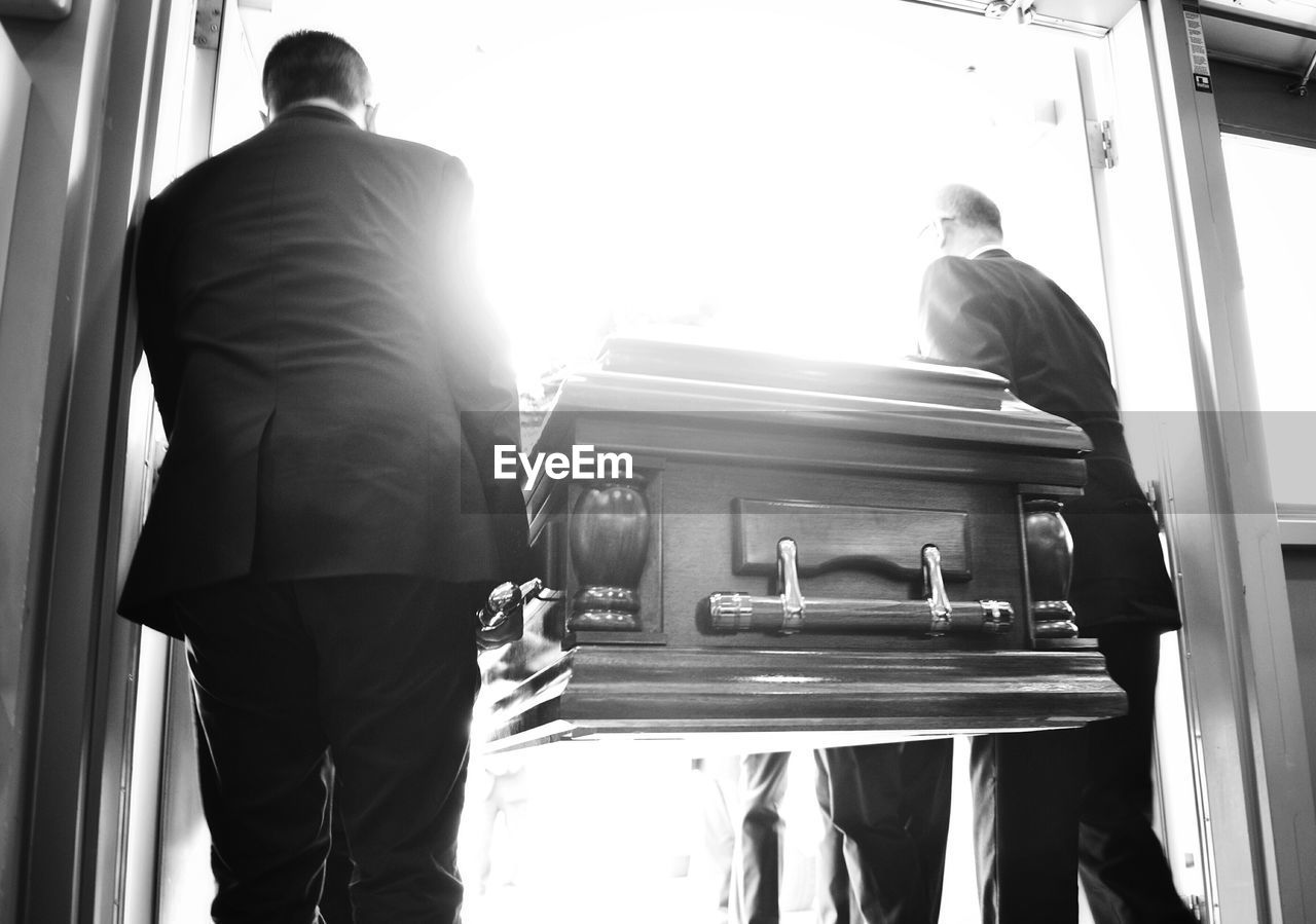 Rear view of people carrying coffin