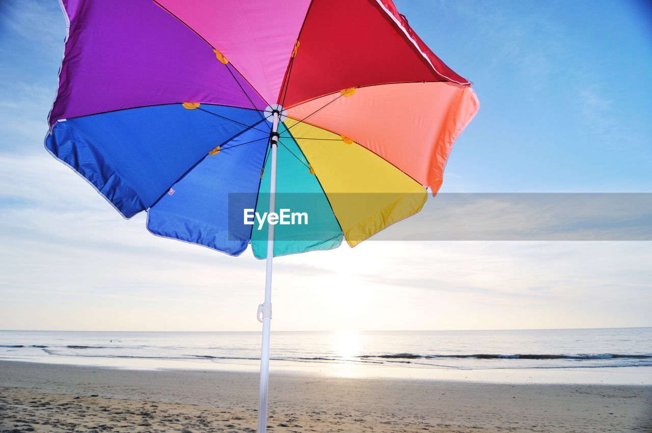 Close-up of umbrella on beach against sky