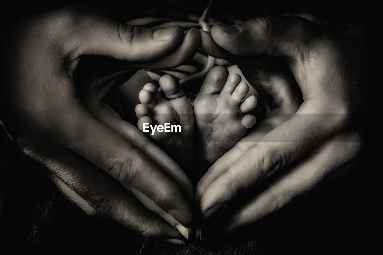 Cropped image of parents hand making heart shape around baby feet