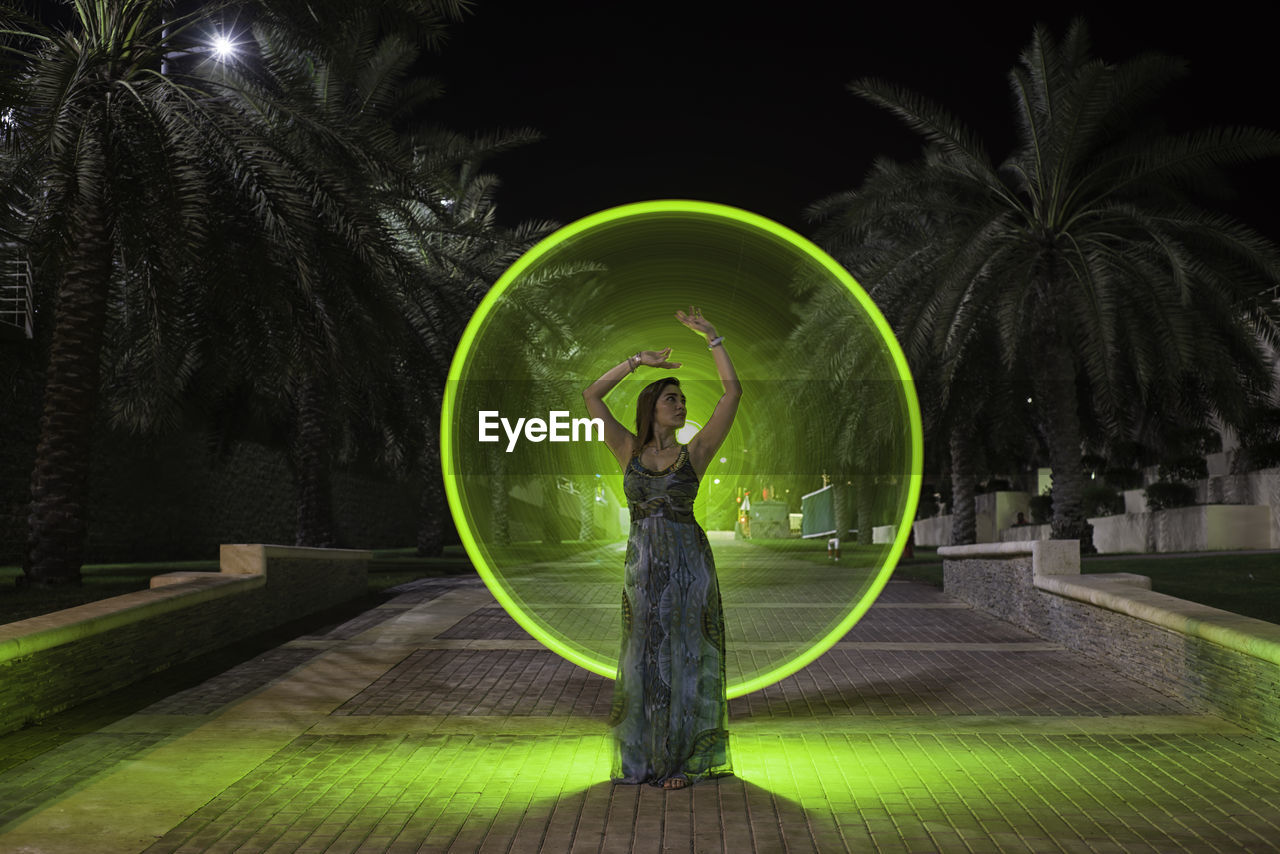 Woman dancing against illuminated lighting equipment at night