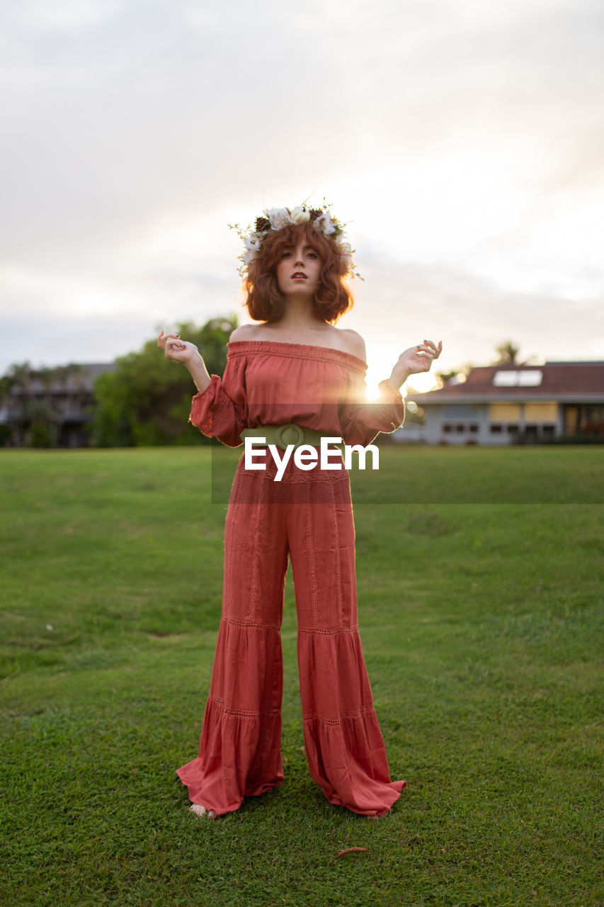 Portrait of woman wearing flowers while standing land during sunset