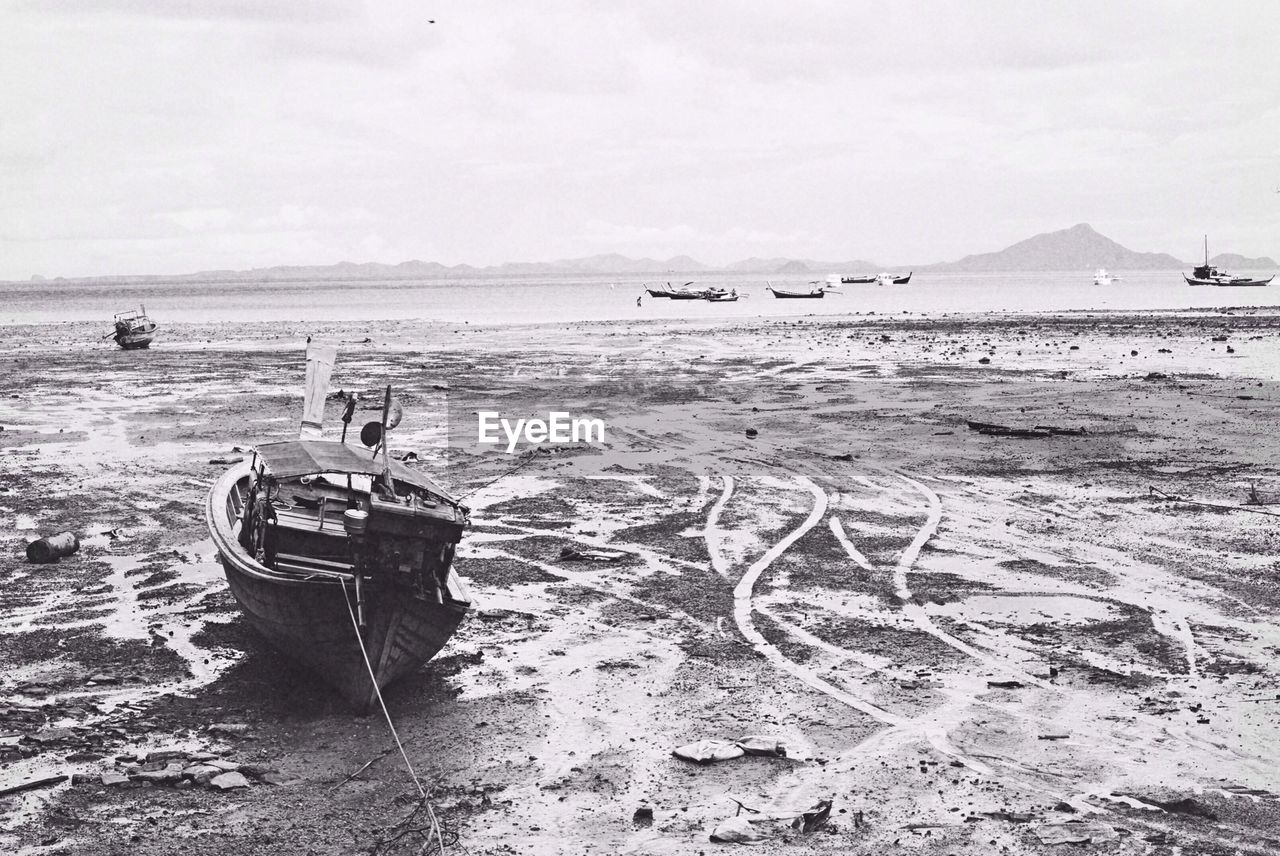 Boat moored at beach against sky