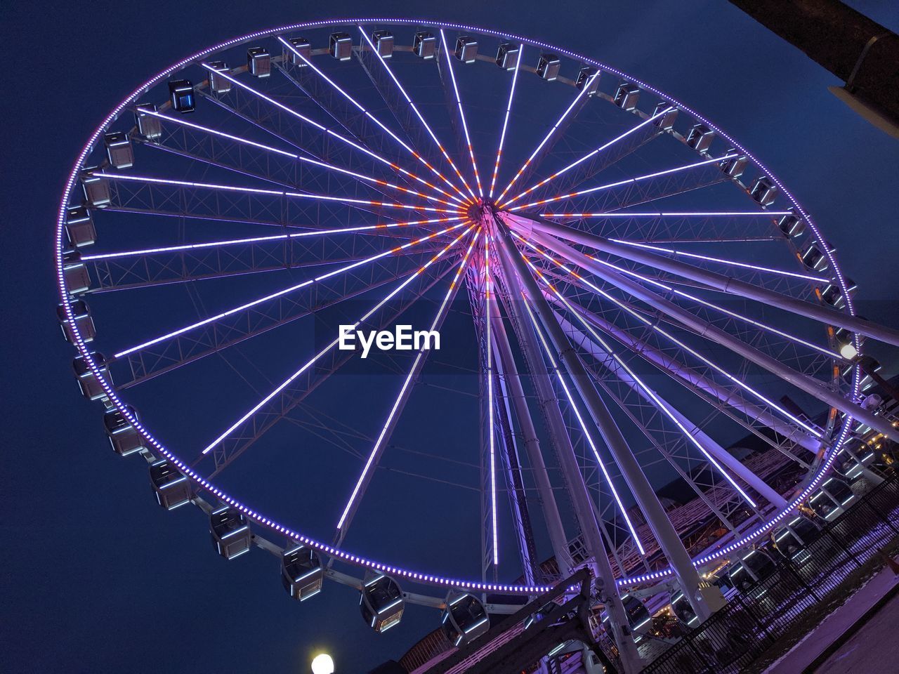 LOW ANGLE VIEW OF ILLUMINATED FERRIS WHEEL AGAINST BLUE SKY