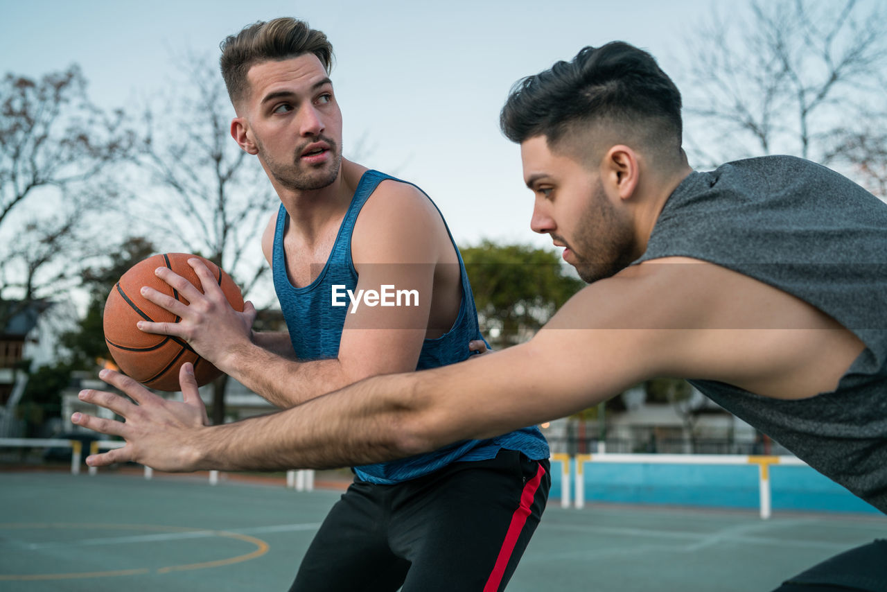 Close-up of men playing basketball outdoors