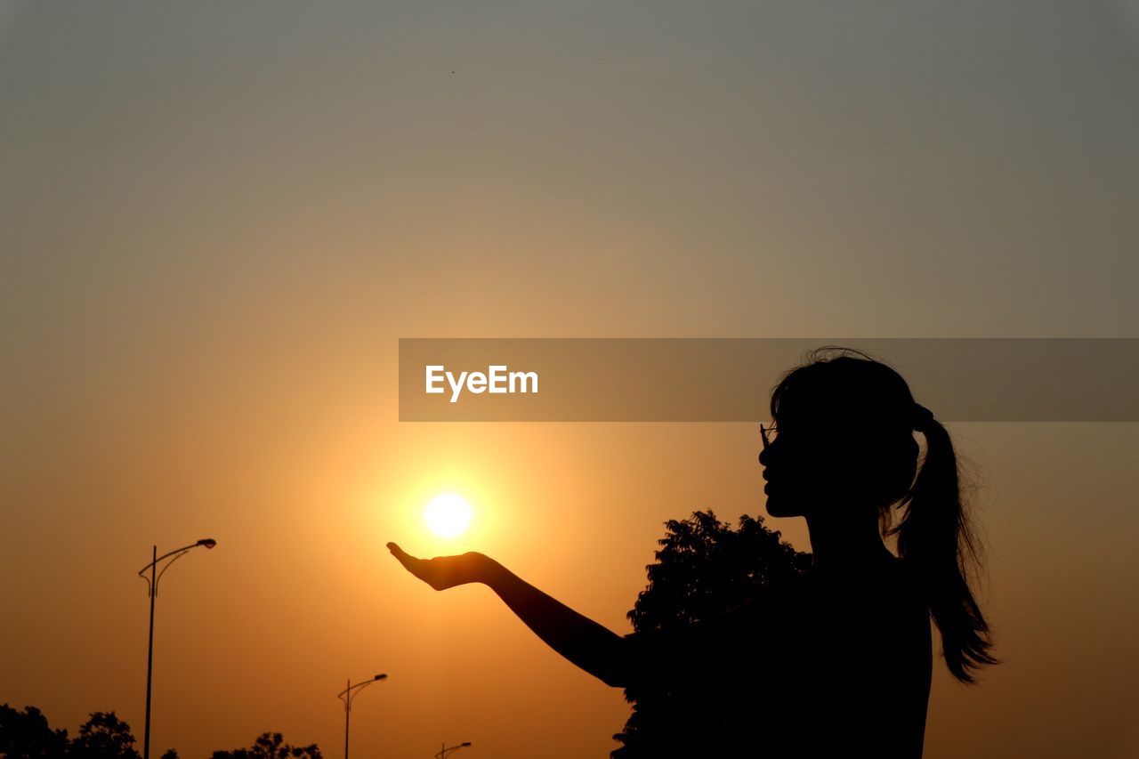 SILHOUETTE WOMAN STANDING AGAINST ORANGE SKY