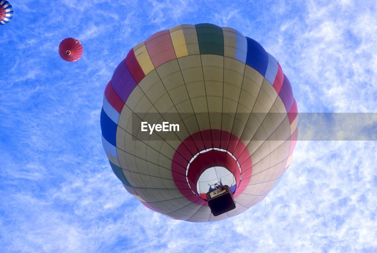 Low angle view of hot air balloons flying against cloudy sky