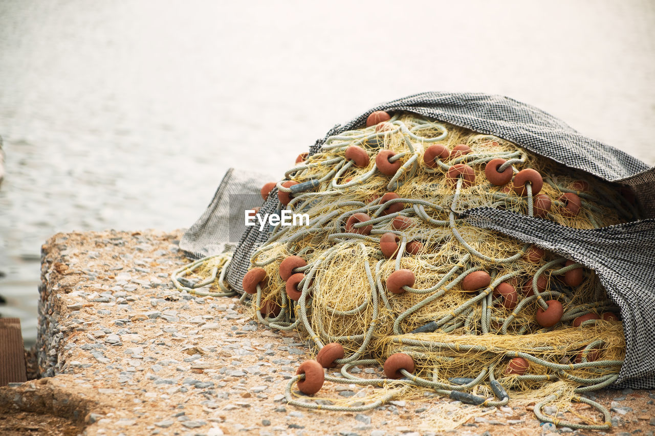 CLOSE-UP OF FISHING NET BY SEA