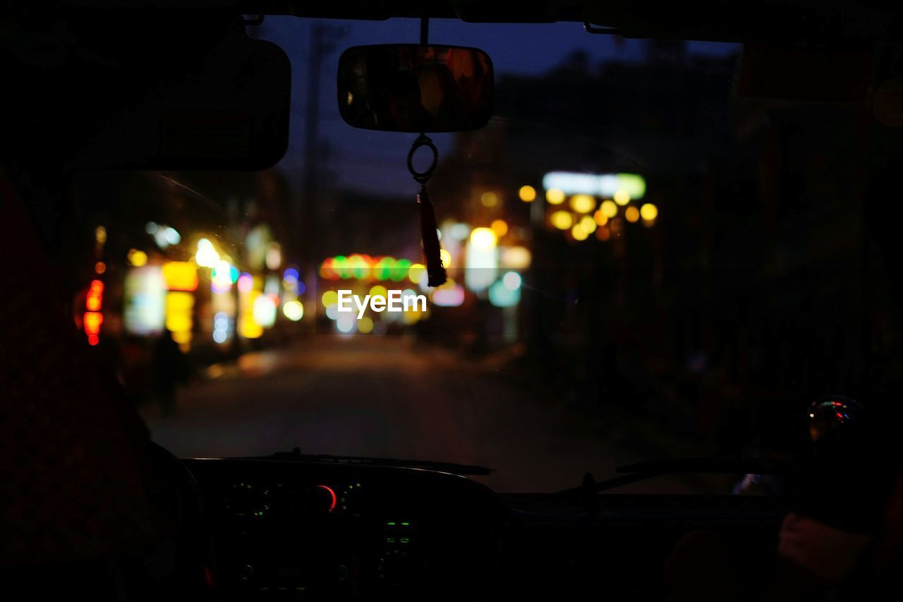 Illuminated stores seen through car windshield at night