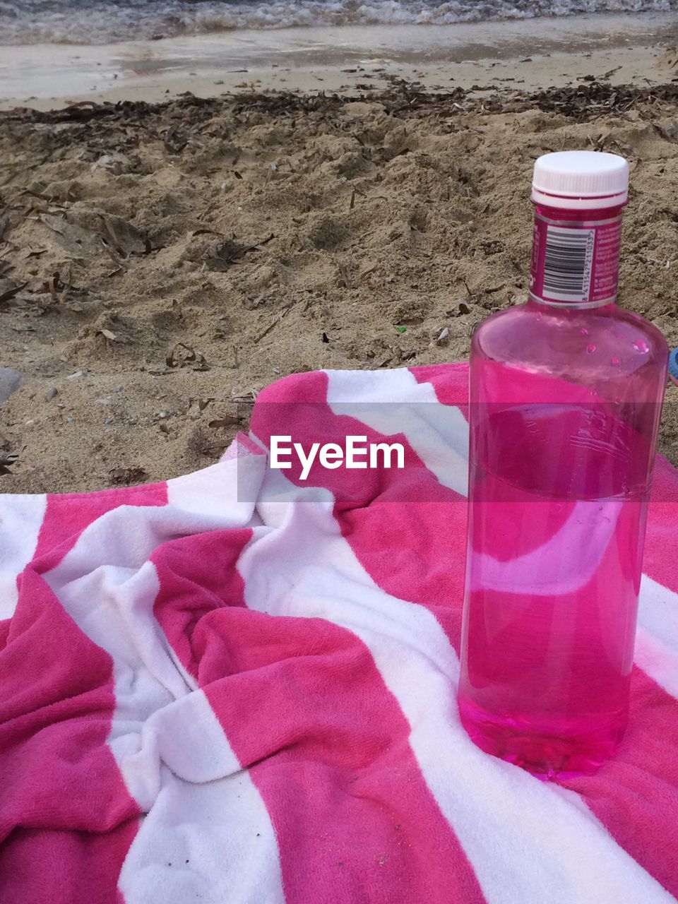 Close-up of red bottle on sand at beach