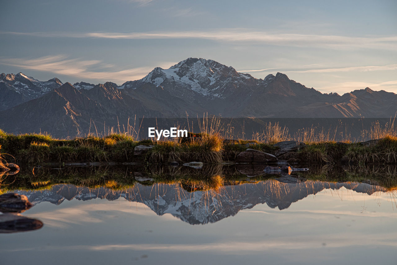 Scenic view of lake by mountains against sky during sunset