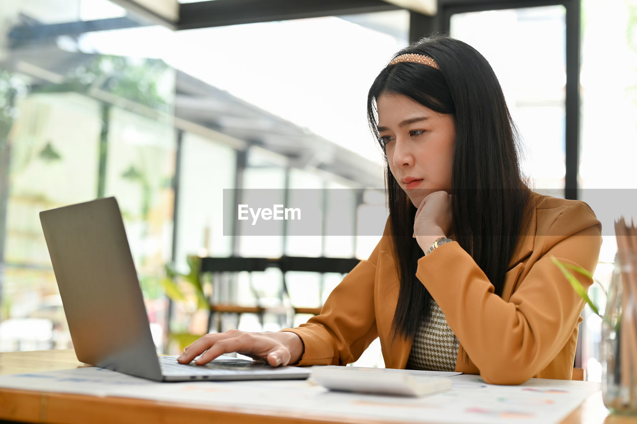 young businesswoman using laptop while sitting on table