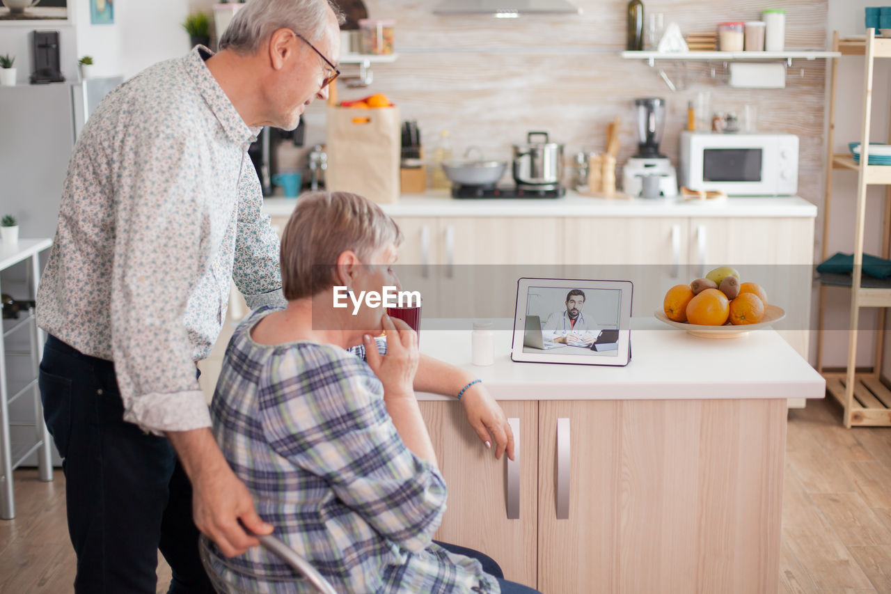 Senior couple video conferencing with doctor over laptop on table