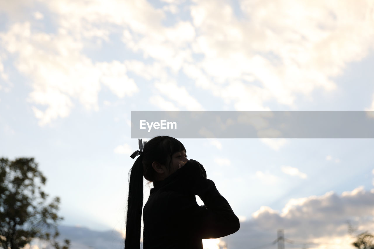 Side view of woman standing against sky