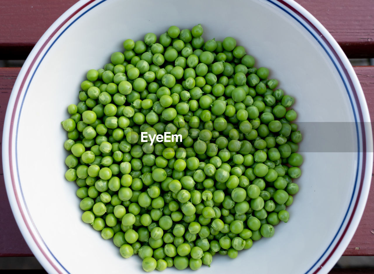 Shelled green peas in a white dish.