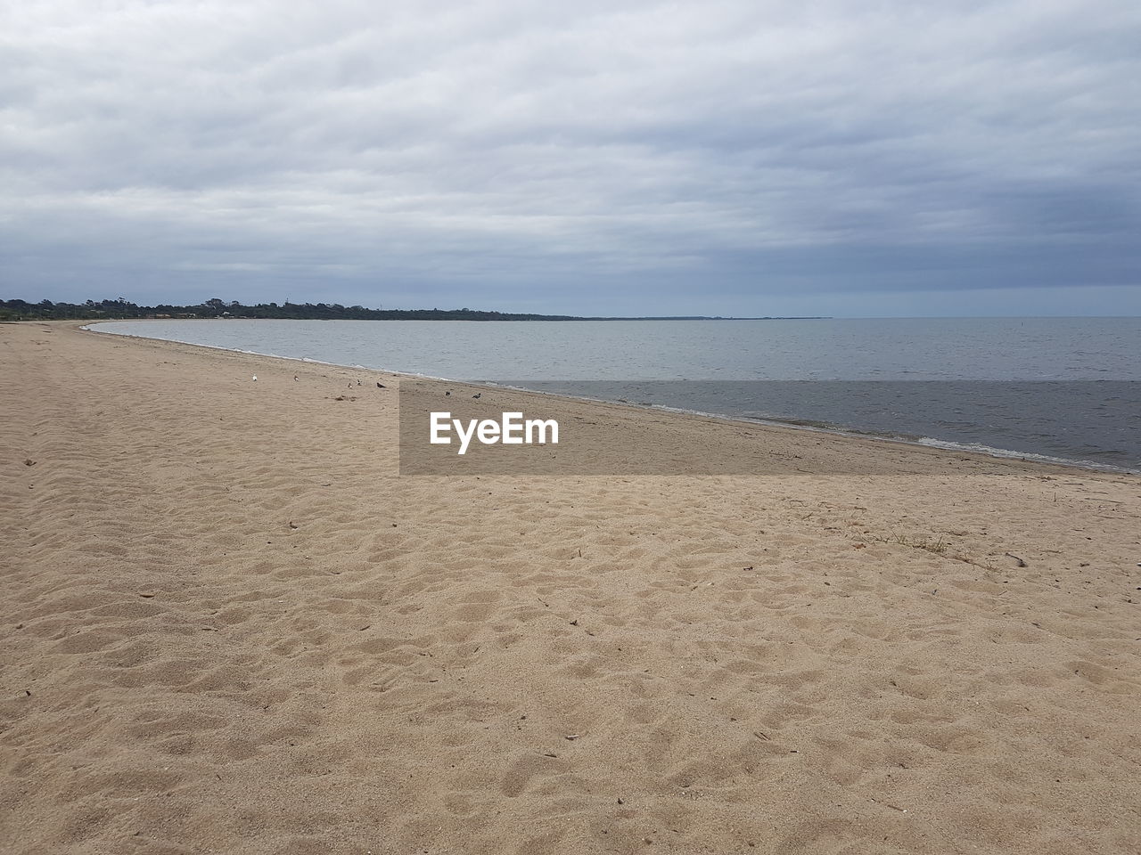 VIEW OF BEACH AGAINST CLOUDY SKY