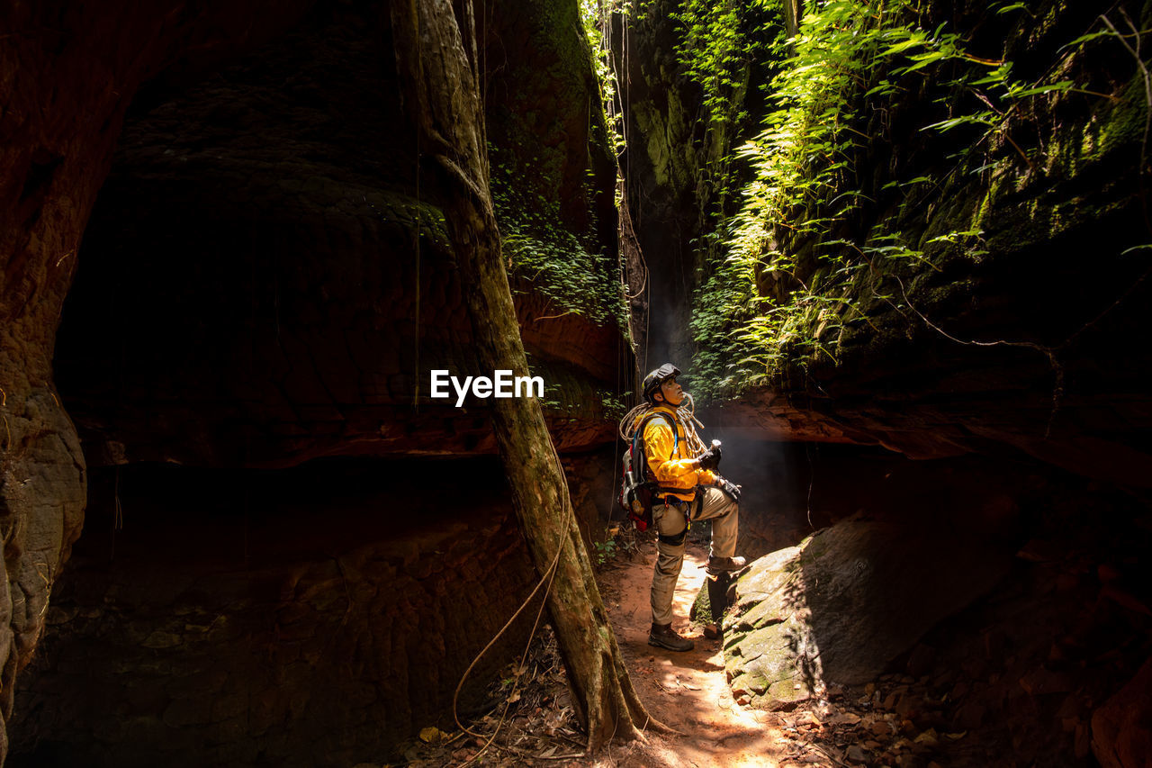 MAN STANDING ON ROCK IN CAVE