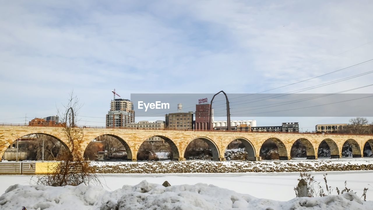 Snow covered arch bridge against sky