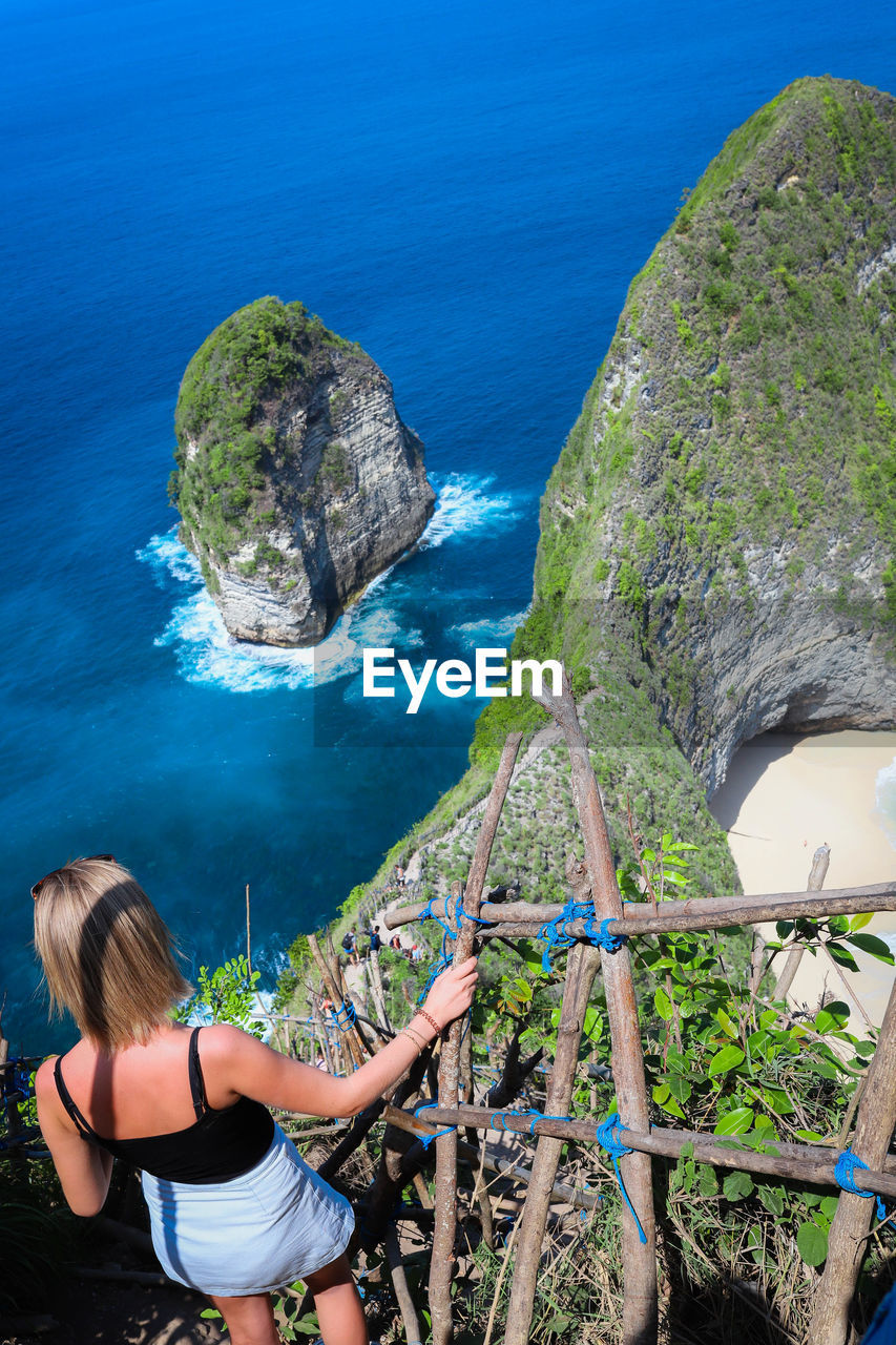 HIGH ANGLE VIEW OF WOMAN LOOKING AT SEA