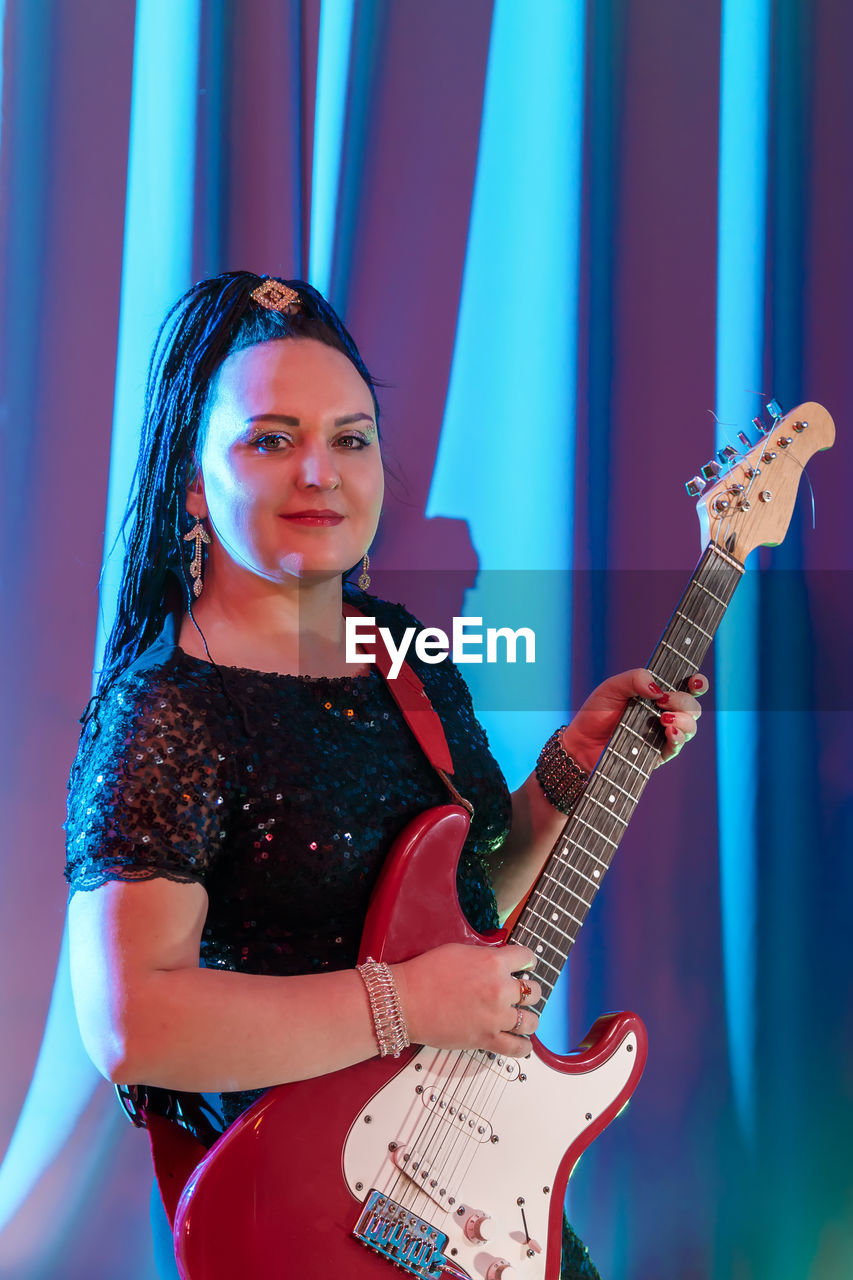 Portrait of young woman playing guitar