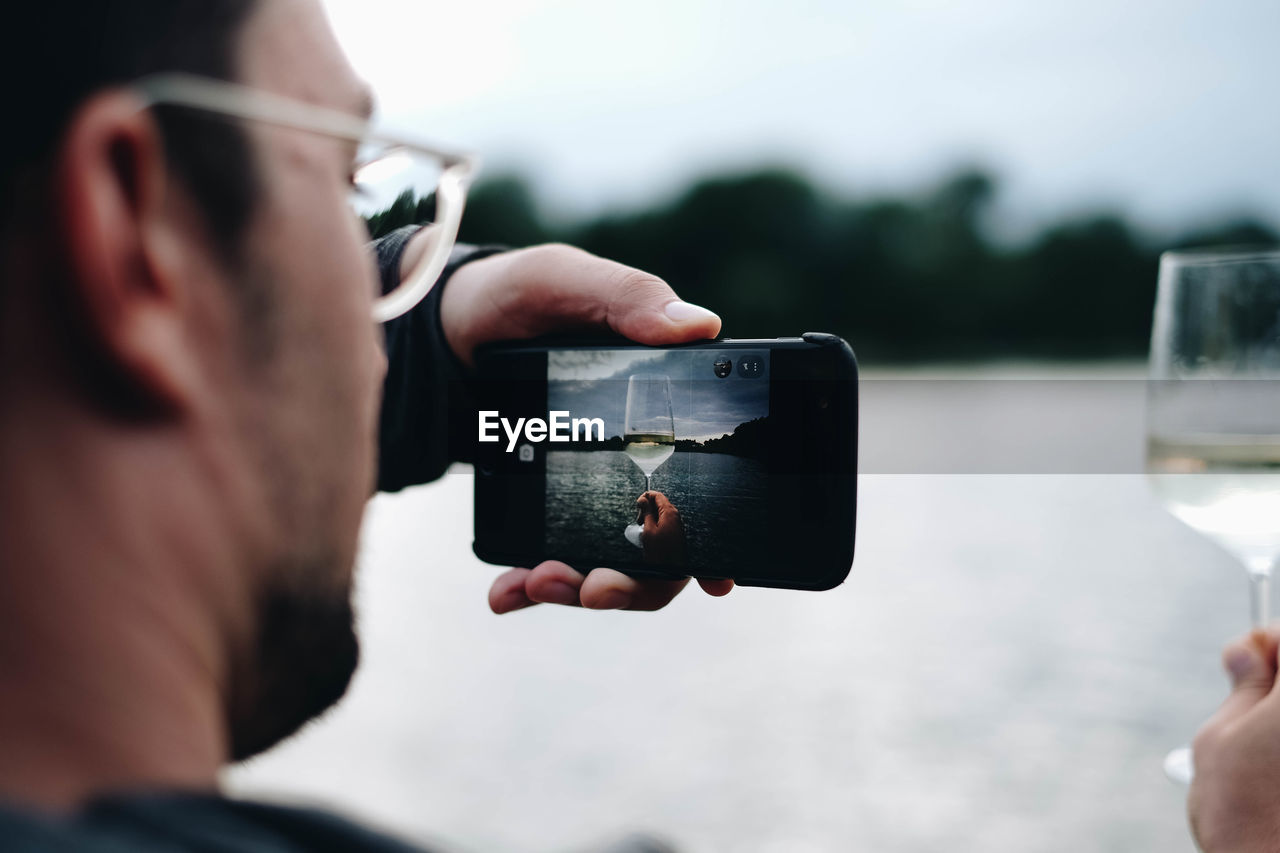 Man photographing wineglass through mobile phone