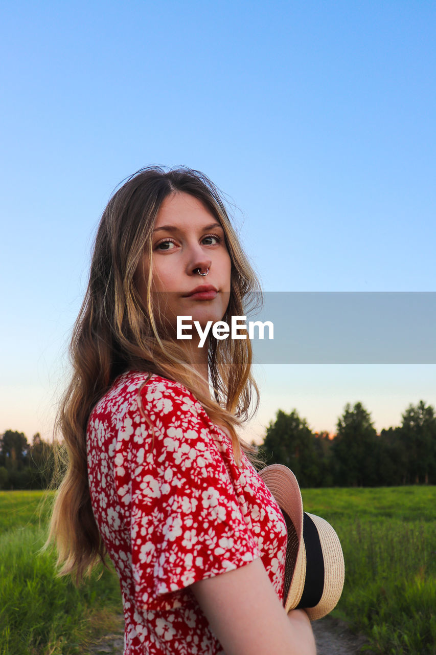 Portrait of beautiful woman on field against clear sky