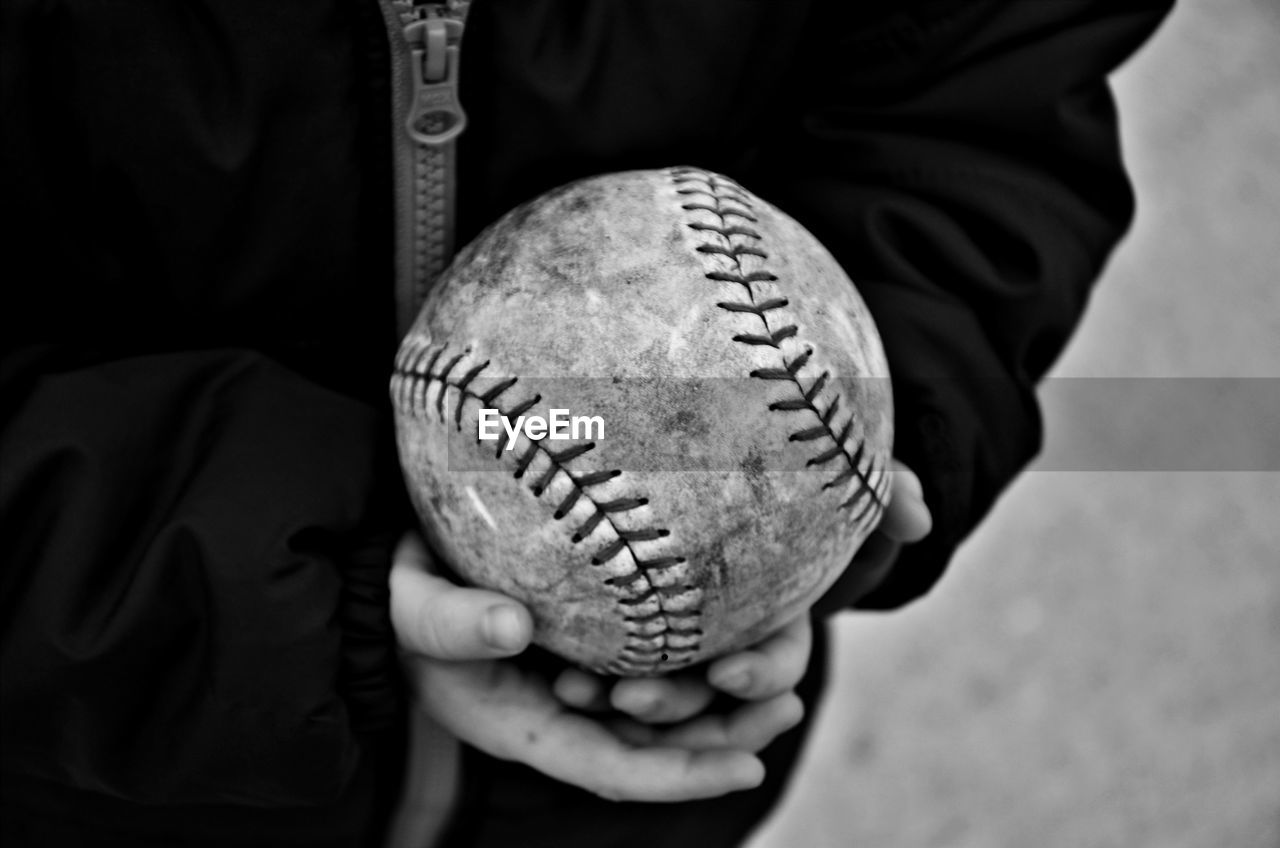 Midsection of child holding baseball