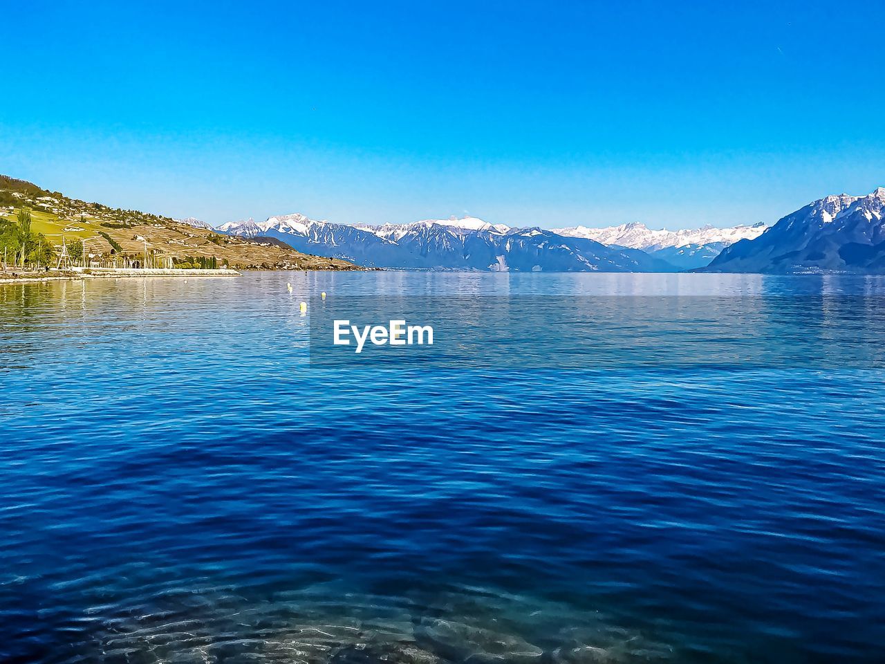 Scenic view of lake against clear blue sky