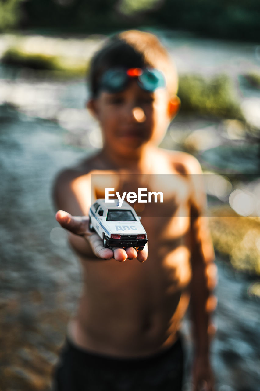 Shirtless boy showing toy car