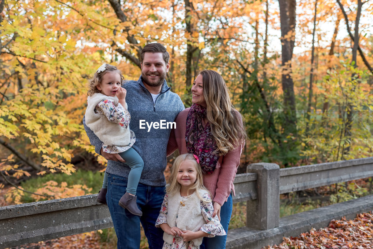 Portrait of smiling family standing against trees