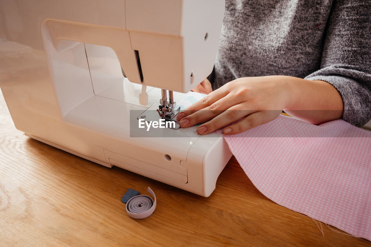 Midsection of woman using sewing machine