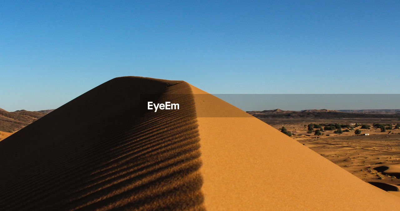 View of desert dunes against clear blue sky