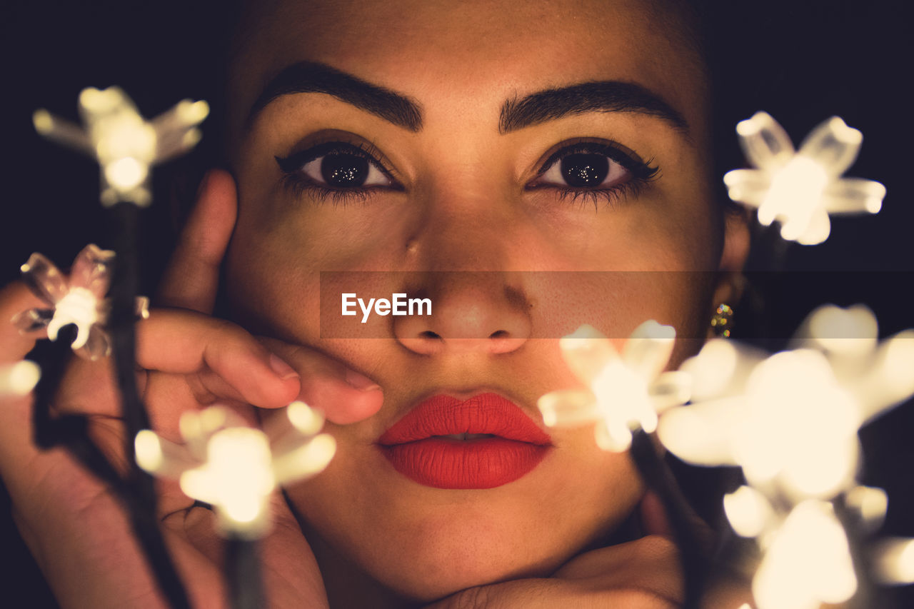 Close-up portrait of young woman with illuminated lights