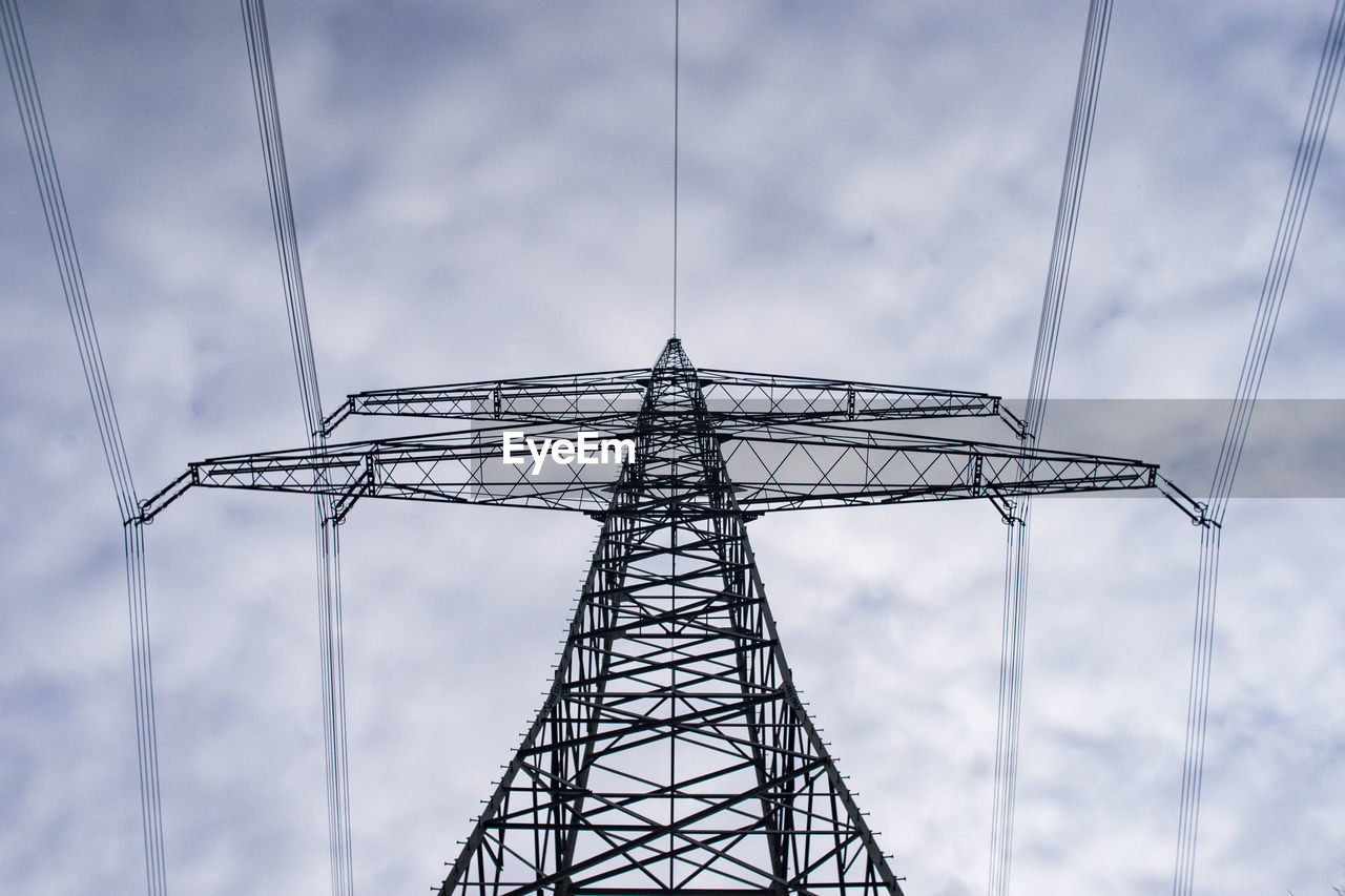 Low angle view of electricity pylon against cloudy sky