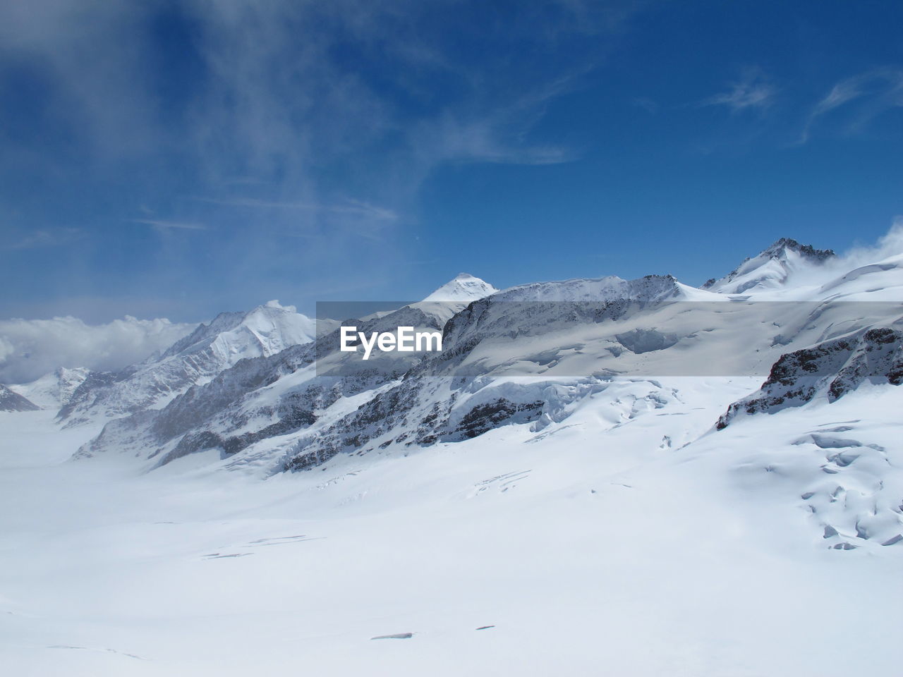 Scenic view of snowy mountains against blue sky