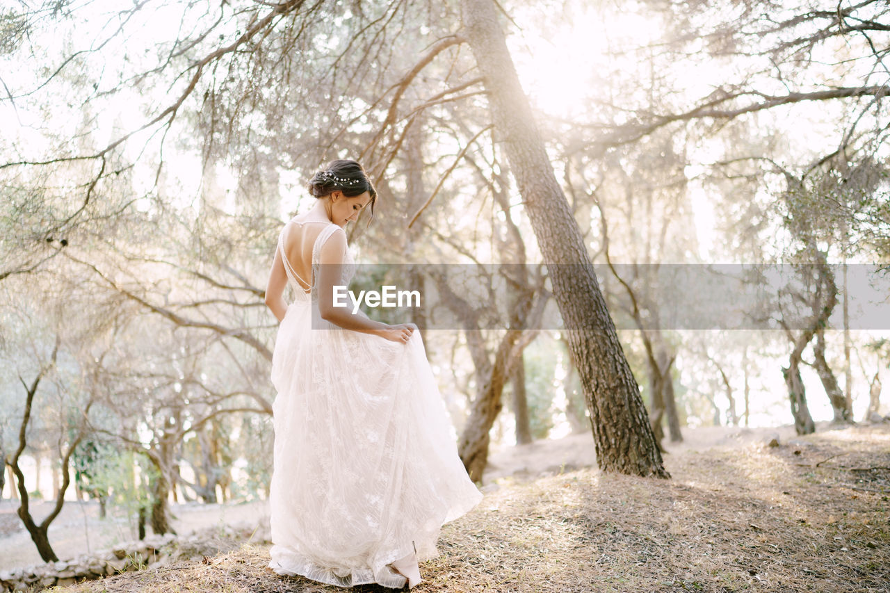 Side view of woman standing against trees