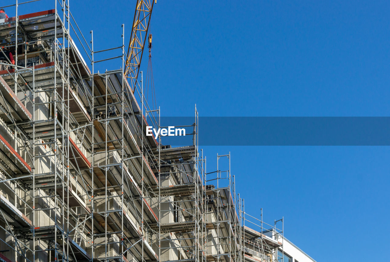 LOW ANGLE VIEW OF CONSTRUCTION SITE AGAINST CLEAR BLUE SKY