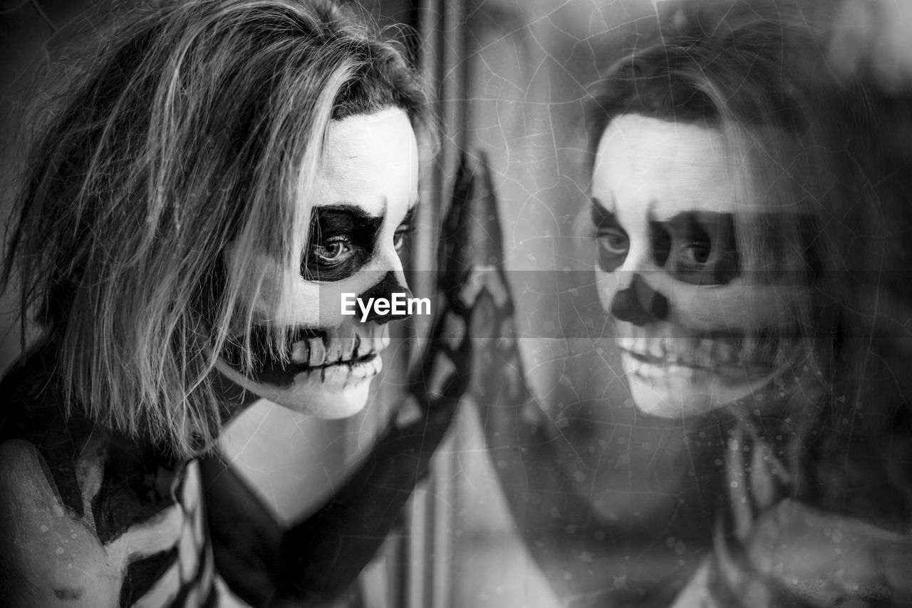 Close-up portrait of a woman in skeleton body paint with reflection on window