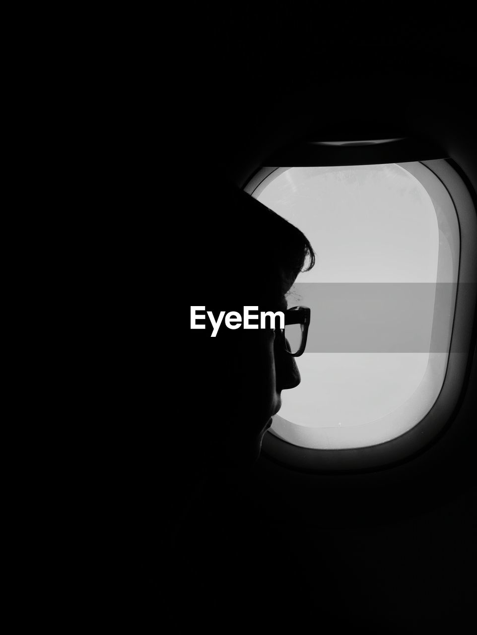 Close-up of teenage boy by window in airplane