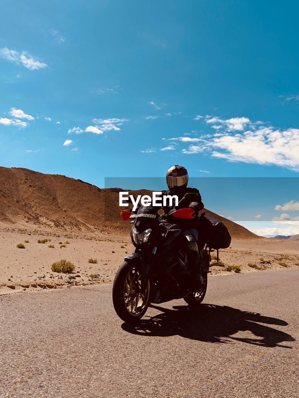 Man riding motorcycle on road against sky