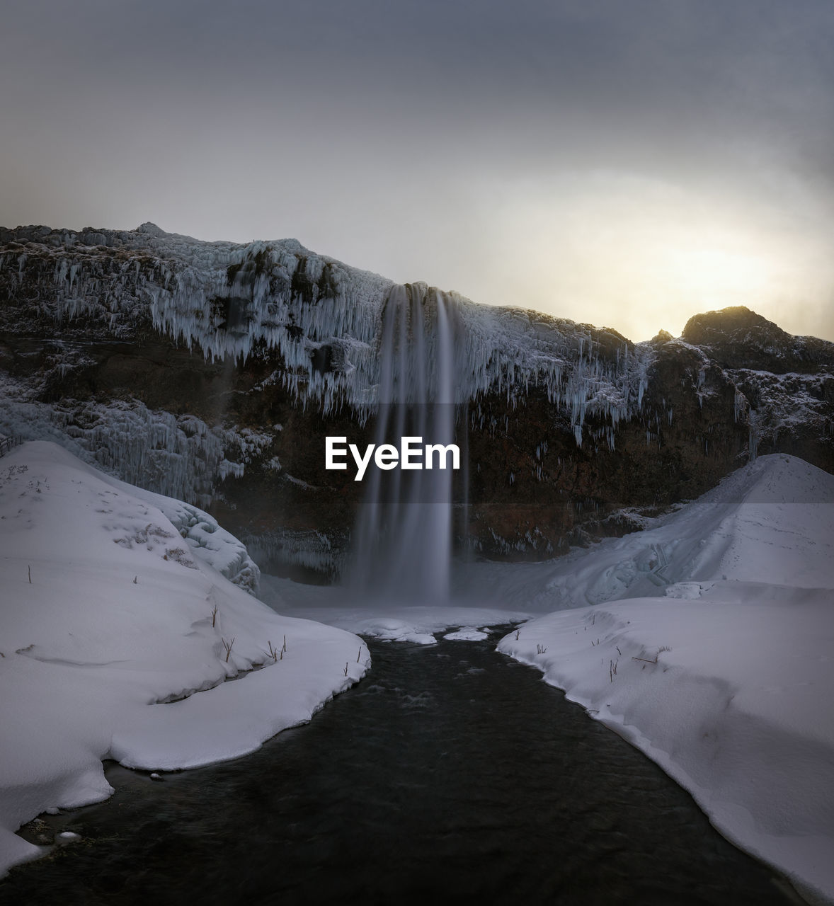 Scenic view of waterfall against sky during sunset