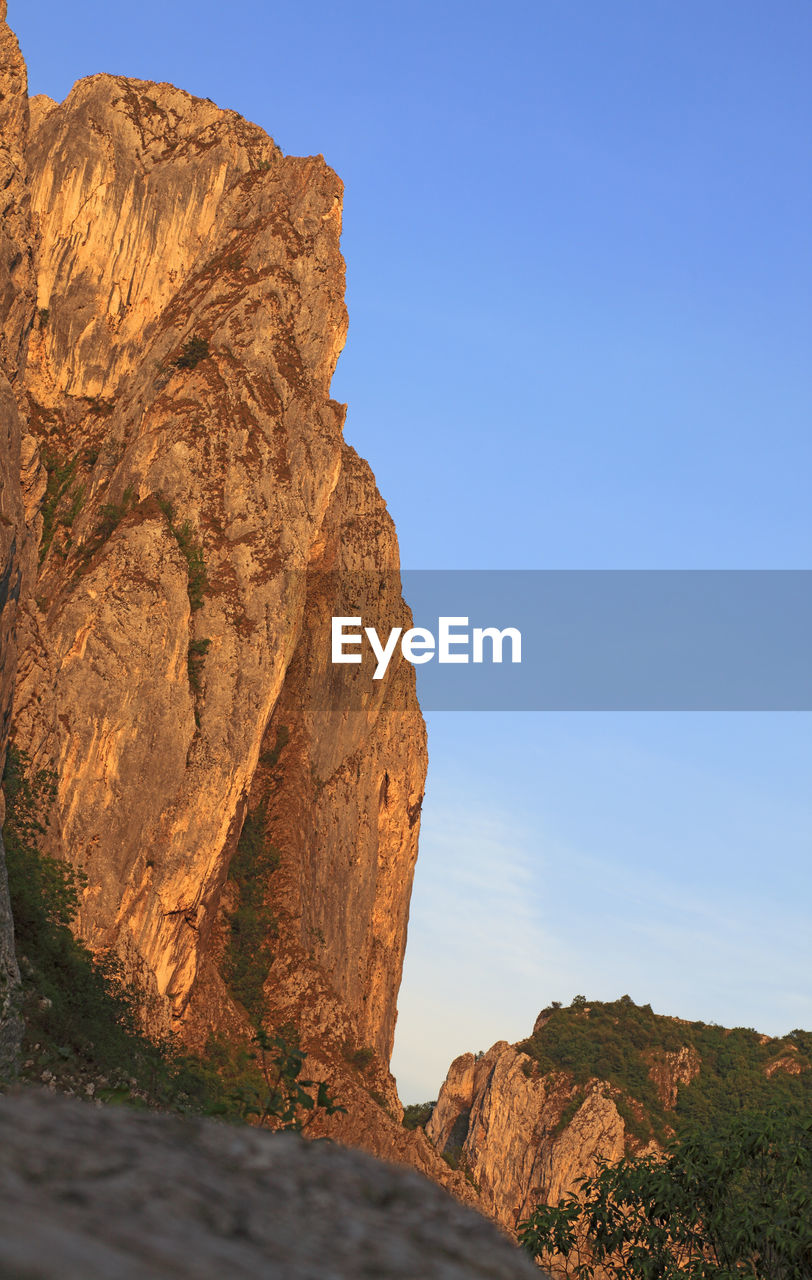 LOW ANGLE VIEW OF ROCK FORMATIONS AGAINST CLEAR SKY