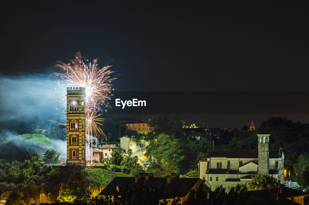 FIREWORK DISPLAY OVER BUILDINGS AGAINST SKY AT NIGHT