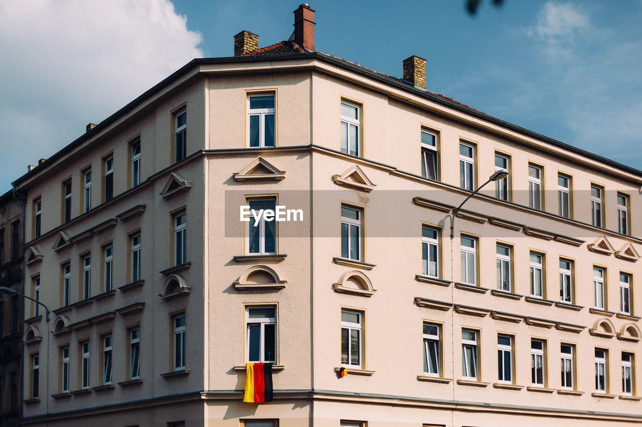 Low angle view of residential building with german flag against sky