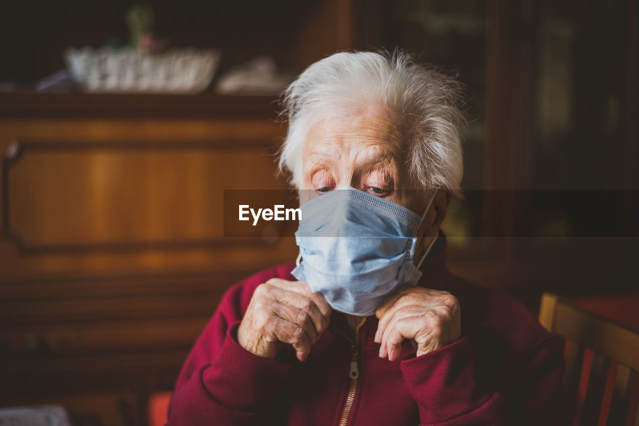 Close-up of woman wearing mask sitting at home