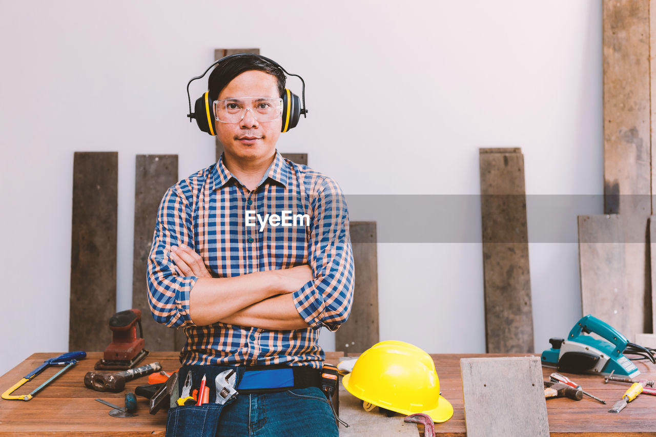 Portrait of carpenter standing with arms crossed at workshop