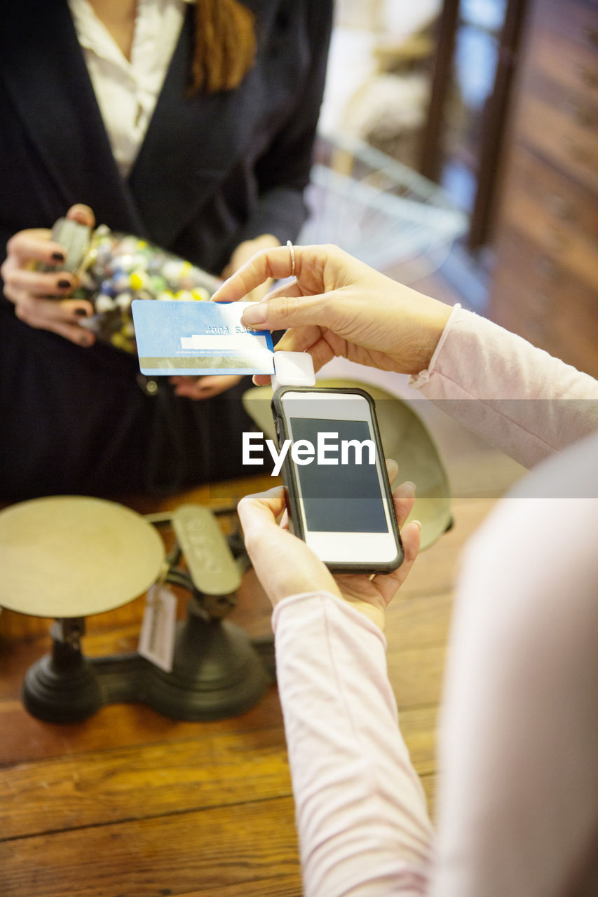 High angle view of woman swiping credit card in credit card reader