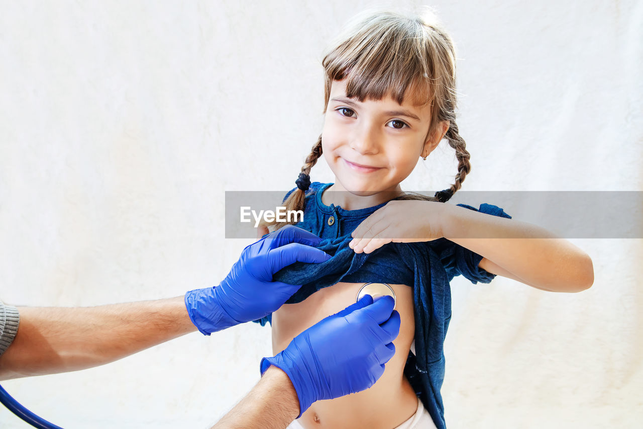 Hand with stethoscope examining girl