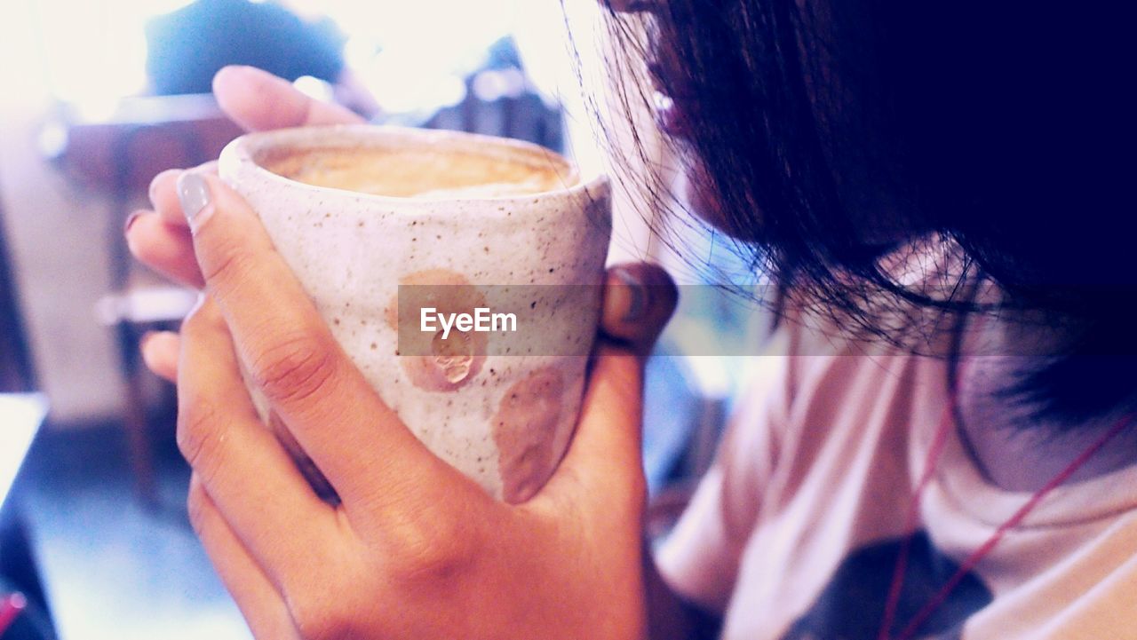 Midsection of woman having coffee in restaurant