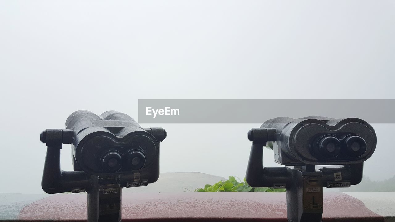 CLOSE-UP OF COIN-OPERATED BINOCULARS AGAINST BUILT STRUCTURE